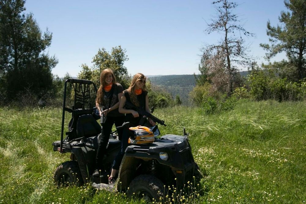 Matzok two girls sitting on ATV in green meadow with Jerusalem hills