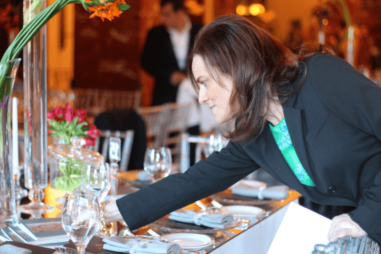 PPenny prepara cuidadosamente una mesa elegante con cristalería, flores y decoración para una ocasión especial en Israel.enny carefully arranging an elegant table setting with glassware, flowers, and decor for a special occasion in Israel.